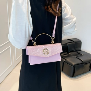 Pink sequin crossbody handbag with gold M buckle and metal handle on a model