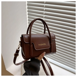 Detailansicht der braunen Kunstleder-Handtasche mit goldenem FASHION-Logo und Griff