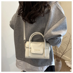 Détail du petit sac blanc minimaliste avec texte FASHION doré et double poignée