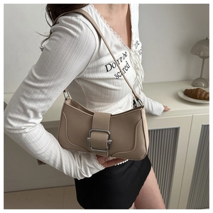 Détail du sac sous le bras beige avec boucle argentée portée par le mannequin sur l'épaule