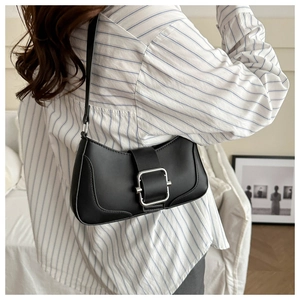 Close-up of black baguette underarm bag featuring a wide strap and silver metal buckle