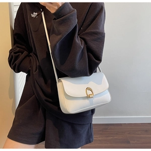 Close-up of white leather saddle bag featuring a minimalist gold-toned crescent metal clasp