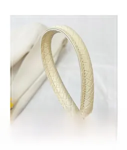Close-up of the elegant woven handle detail on a creamy white faux leather handbag