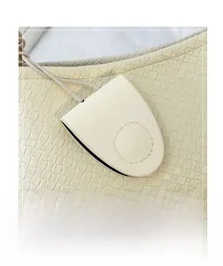Detailed view of beige woven texture handbag with matching leather eyewear pouch accessory