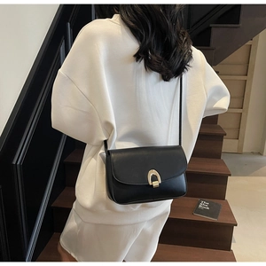Close-up of black leather saddle bag featuring a striking gold horseshoe metal buckle