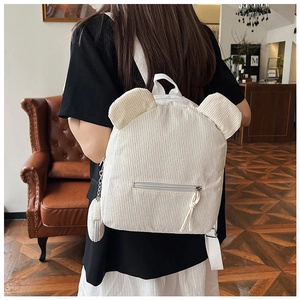 White corduroy backpack detail showing cute bear ears and round coin purse pendant