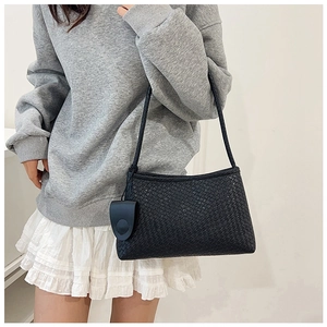 Minimalist black woven shoulder bag styled on model for a trendy commute look