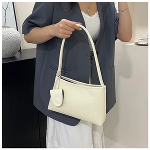 Detail of cream woven texture underarm bag with matching mini round coin purse pendant