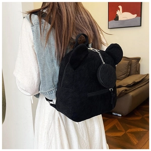 Seitenansicht des schwarzen Cord-Rucksacks mit Bärenohren und kleiner Kettentasche