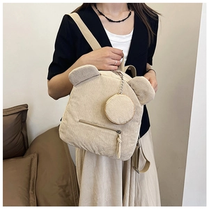 Detail of beige corduroy bucket bag featuring bear ears and a round chain coin purse charm