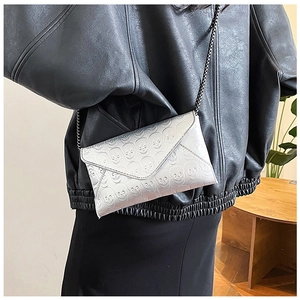 Silver skull-embossed envelope clutch bag with black chain strap shown on model