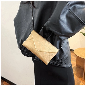Close-up of beige envelope crossbody bag with skull embossing and metal chain strap
