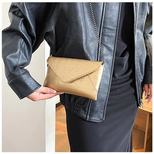 Detail of gold envelope crossbody bag with skull embossing and metal chain strap