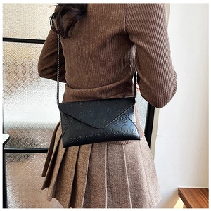 Close-up of black envelope crossbody bag featuring detailed 3D skull embossed patterns