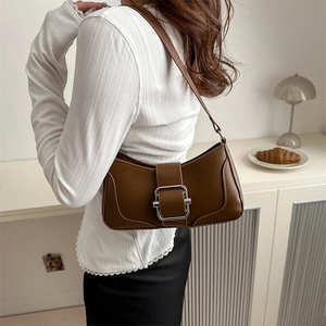 Sac bandoulière marron en cuir avec boucle argentée vintage porté par un mannequin chic