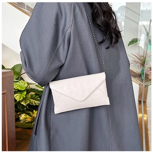 Detail of white envelope clutch bag with skull embossed pattern and metal chain strap