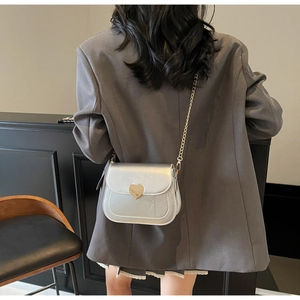 Silver mini saddle bag featuring gold heart-shaped buckle and metal chain strap details