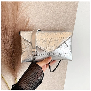 Detail of silver envelope bag with skull embossing and metallic chain strap