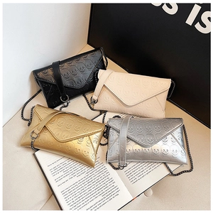 Close-up of four skull embossed envelope clutch bags in black, white, gold, and silver colors