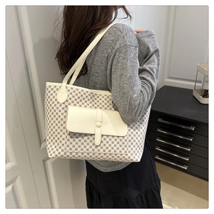 Detailed side view of a beige tote bag with geometric dots and front leather pocket