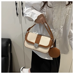 Detail of contrast stitch saddle bag featuring woven fabric and a round coin purse charm