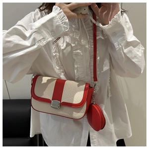 Detail of red and cream woven crossbody bag with mini coin purse shown on a model