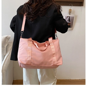 Rückansicht eines Models mit einer großen rosa Nylon-Schultertasche mit gewebtem Griff