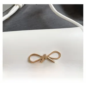 Detailed close-up of white leather handbag featuring a golden bow metal buckle fastener