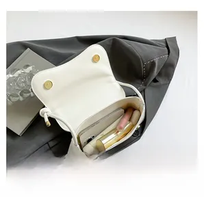 Detail showing inner capacity of white bow shoulder bag with phone and cosmetics