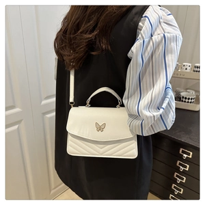 Detail showing white PU leather handbag with butterfly metal buckle and V-quilted pattern