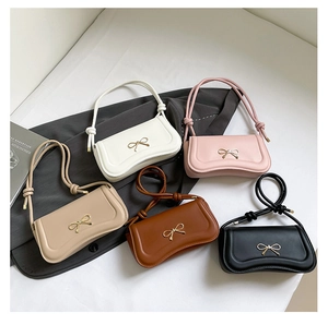 Detail view of stylish crossbody bags with metallic bow accent and knotted straps in five colors