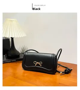 Detail of black leather handbag with golden bow buckle on a warm wooden desk