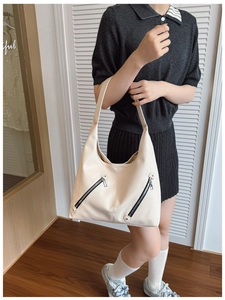 Detail of cream lychee leather texture and dual metal zippers on large tote bag
