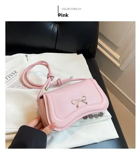Close-up of pink PU leather handbag with metal bow detail and knotted shoulder strap