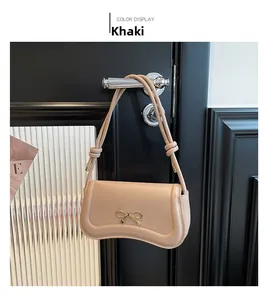 Close-up of khaki shoulder bag featuring a gold bow buckle on a dark door handle