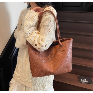 Close-up of brown woven tote bag with dual shoulder straps on a rustic wooden staircase