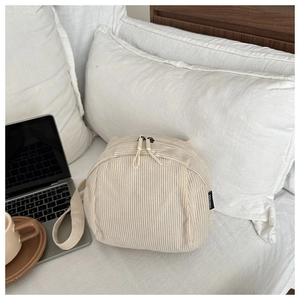 Detail of off-white corduroy shell bag texture with double zipper and woven brand label
