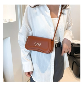 Detailed close-up of brown crossbody bag with a distinctive metal bow clasp for women