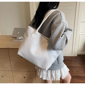 Detailed close-up of white woven tote bag with geometric grid texture and wide shoulder strap