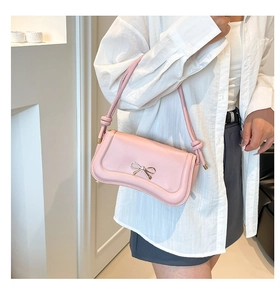 Close-up of pink bow baguette bag with delicate metal clasp and knot strap detail