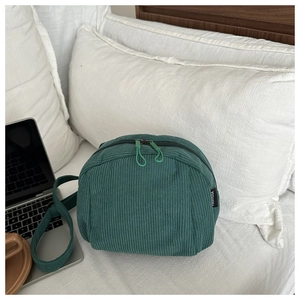 Detailed macro view of dark green corduroy texture and dual zipper on the stylish shoulder bag
