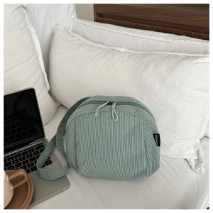 Detail of light green corduroy shell bag featuring durable zippers and a woven brand label
