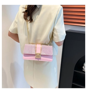 Detail of pink crossbody bag with sequins and gold chain strap worn with beige suit