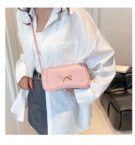 Detail of pink bow handbag showing refined golden bow accent and smooth PU leather texture