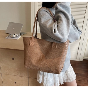 Close-up of brown tote bag with woven texture pattern on a desk with laptop