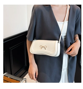 Close-up of a white sweet bow shoulder bag featuring a golden metal bow buckle decoration