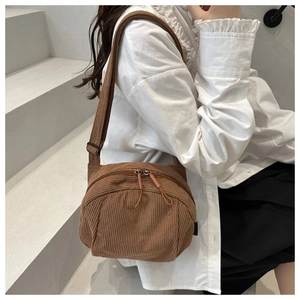 Brown corduroy crossbody bag with double zippers and adjustable strap on a model