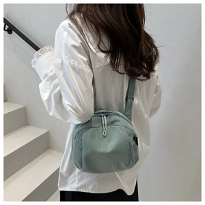 Detail of sage green corduroy shell bag texture and adjustable wide shoulder strap