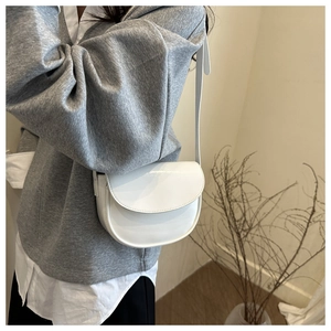 Detail of minimalist white saddle bag with smooth leather finish and matching shoulder strap