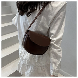 Close-up of the vintage brown saddle bag with smooth leather texture and curved flap detail